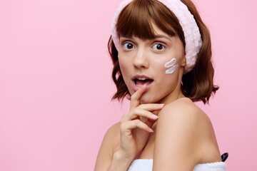 Wall Mural - Horizontal studio shot. a beautiful woman with smooth skin, a beautiful smile and dark wavy hair is standing on a pink background with a pink headband is smiling.