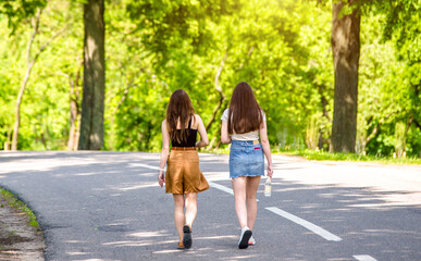 Wall Mural - Two girlfriends walk along a path in the Park
