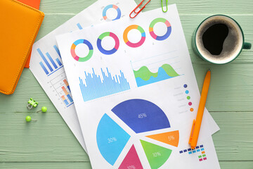 Poster - Business charts, cup of coffee and stationery on green wooden background