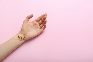 Wall Mural - Female hand with plasters and word FOOD on color background. Anorexia concept