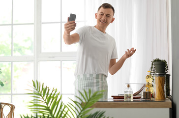 Sticker - Young man with mobile phone taking selfie in kitchen