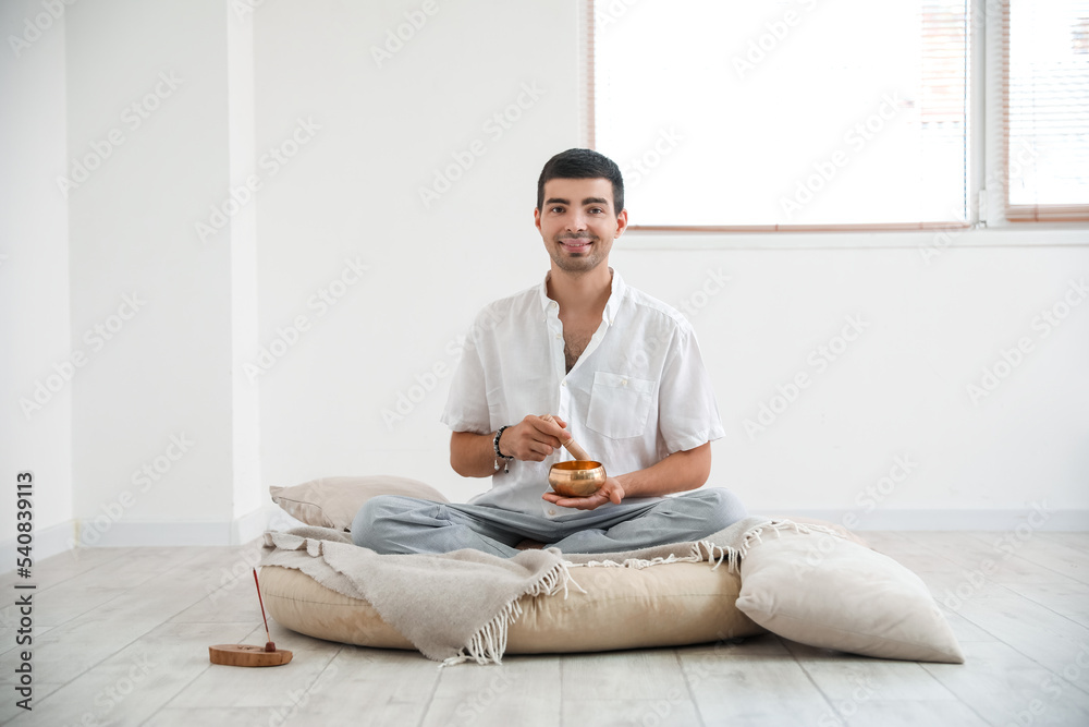 Young man with Tibetan singing bowl at home