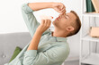 © Pixel-Shot - Young man with nosebleed and tissue at home