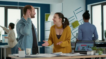 Wall Mural - Smiling coworkers in startup office doing high five hand gesture celebrating good sales and high profit standing at desk. Happy colleagues enjoying team work looking at business papers with charts.