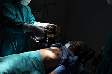 Closeup image of professional concentrated surgical team performing CPR with defibrillator on patient in hospital operating room or emergency room. Surgery concept