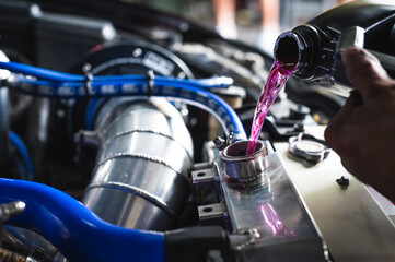 Auto mechanic filling pre-mixed long life coolant fluid in to aluminum radiators.