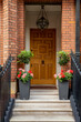 Brown front door, entrance to the house with potted flowers