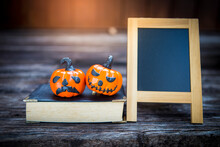 Halloween Concept Background, Funny Halloween Pumpkin On Old Book With Chalkboard With Space On Wood Background