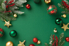 Christmas Tree Decorations Concept. Top View Photo Of Red Gold Green Baubles Star Ornaments Mistletoe Berries And Pine Branches In Hoarfrost On Isolated Green Background With Copyspace In The Middle