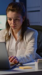 Poster - Vertical video: Business woman working overtime to respect deadline of project sitting in business office typing on laptop late at night. Busy focused employee using modern technology network wireless