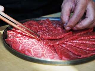 The  chef making raw beef  slices with marbled texture