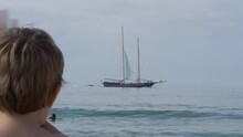 Caucasian Boy Child Looking On A Vintage Ship Sailing On Sea Surface From Distance. Back View, Wide