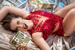 Sensuous woman in red dress with Christmas gifts lying on bed