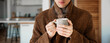 © ProstoSvet - a man in a warm coat with a hot mug of coffee or tea in his hands is trying to warm himself at home. Home heating shutdown concept. Gas shutdown.