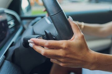 Wall Mural - Woman's hand switches the lobes of the gear selector on the steering wheel. Hand is switching car gear lever, close up shot of a manual gear changing paddle on a car's steering wheel.