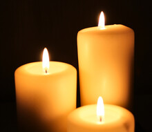 Three Candles Burning On A Black Background