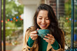 © olga pink - Portrait of cute young Asian woman drinking coffee on terrace of cafe. Outdoors. Cozy autumn season
