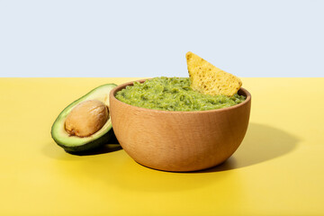 Wall Mural - Mexican guacamole with nacho chip on yellow background