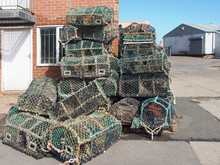 Lobster Pots Used In Traditional Fishing For Crustaceans Stacked Against A Dockside Building In Scarborough Harbour