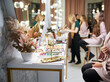 Dressing table with makeup brushes, glass of alcoholic drink and corporate business chocolate on gold tray. Champagne, sweets and makeup artist tools in beauty salon.