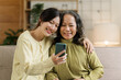 © NanSan - Mature asian mom with daughter on video call to parents, loving mother day concept.
