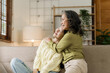 © NanSan - Asian mature woman hugging with daughter while sitting on sofa, mother day concept.