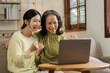 © NanSan - Asian mature mom with daughter using laptop while sitting on sofa, mother day concept.