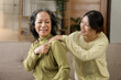 © NanSan - Asian daughter giving an elderly mother a relaxing massage while sitting on the sofa