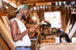 excited african man with smart phone in a workshop- local black guy enjoying social media