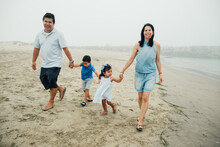 Family Of Four Walking Along The Coast Holding Hands Foggy Day