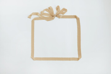 Frame of beige ribbon with bow on white background. Blank copy space mockup template