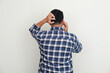 Back view of adult man scratching his head while answering a phone call