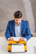 © gzorgz - Man sitting at desk and using retro typewriter
