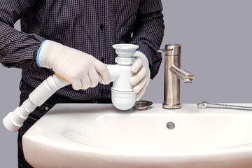 Wall Mural - A plumber installs a siphon for a wash basin in a bathroom