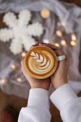 Canvas Print - Top view of a hands holding a cup of coffee with tulip latte art