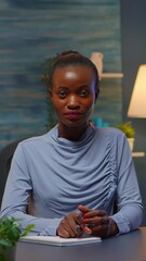 Poster - Vertical video: African freelancer working from home talking on camera sitting at desk in living room late at night. Pov of black entrepreneur having online meeting, webinar with business remotely