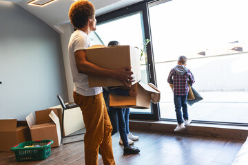 Wall Mural - Mixed race family moving into their new home. They're carrying cardboard full of their accessories.