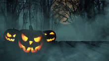 Scary Glowing Pumpkins On Wooden Boards In A Foggy Forest With Moon And Bats. Happy Halloween Creative.