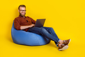 Poster - Full body photo of positive person sit comfy bag use wireless netbook isolated on yellow color background