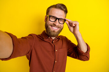 Sticker - Photo of handsome satisfied man with blond beard dressed burgundy shirt doing selfie touch glasses isolated on yellow color background