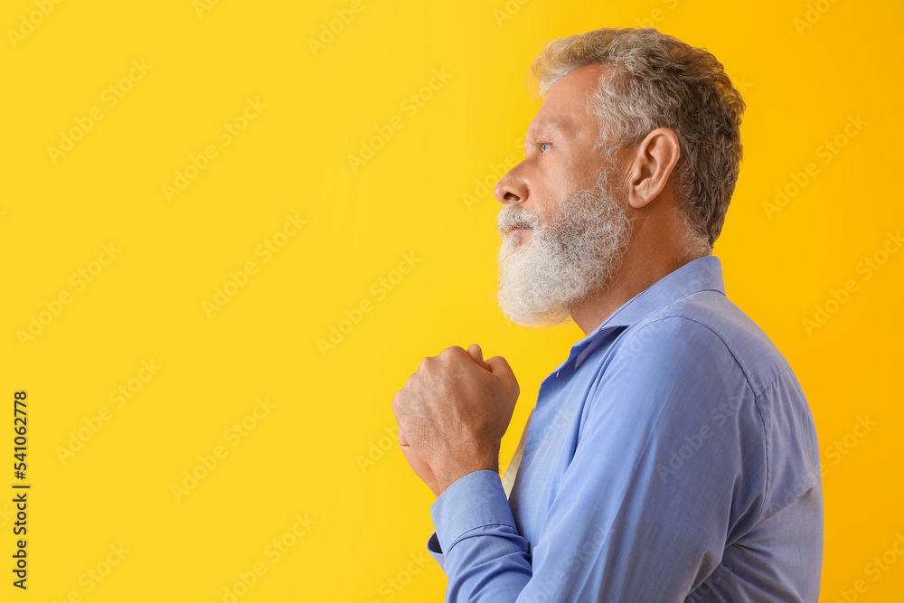 Thoughtful mature man on yellow background