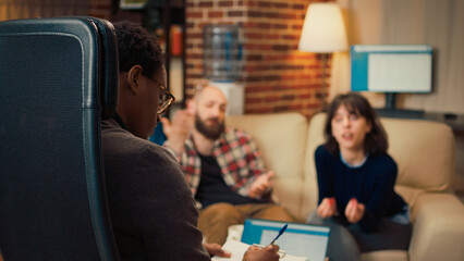 Wall Mural - Male therapist listening to man and woman with problems, trying to solve conflict at couple therapy session. Counseling advisor doing relationship psychoanalysis to save marriage.