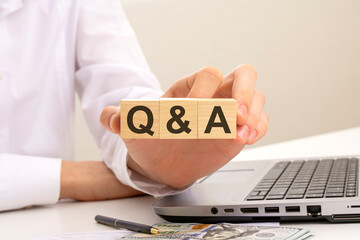 Sticker - hand holds wooden cubes with inscription Q and A - short for Question and Answer, white background. help and tips concept