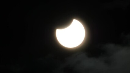 Wall Mural - partial solar eclipse with a small thin layer of clouds moving past the sun - oct. 25, 2022