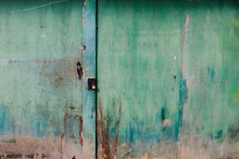 A Large Closed And Locked Wooden Gate With Green And Blue Weathered Paint. 