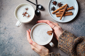 Wall Mural - Homemade chai latte with cinnamon and star anise in white cup, dark background.