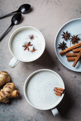 Wall Mural - Homemade chai latte with cinnamon and star anise in white cup, dark background.