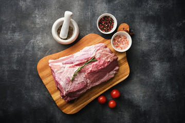 Wall Mural - Raw pork neck chop meat with herb leaves and spices on wooden board. Grey background. Top view.