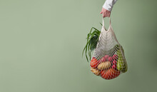 Mesh Bag With Vegetables And Herbs In Female Hand.
