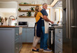 © Nina Lawrenson/peopleimages.com - Senior couple in kitchen hug, cooking healthy food together and care in retirement lifestyle. Elderly man and woman with apron, hugging wife in home or love dinner meal with happy smile in marriage